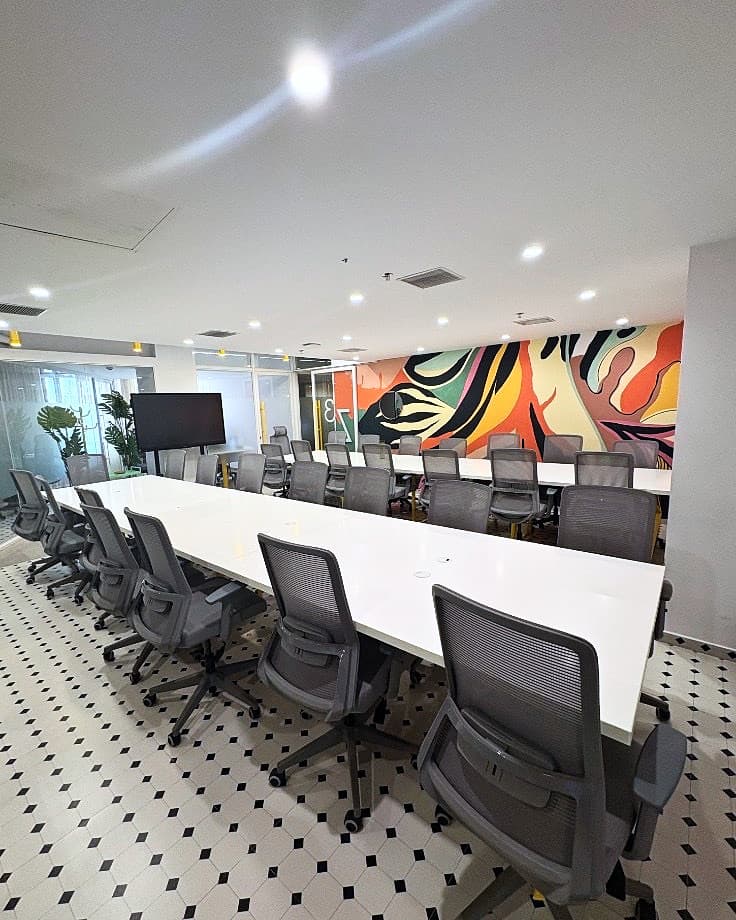 Corrivex meeting bay with white work tables, mesh chairs, and the colourful facility mural