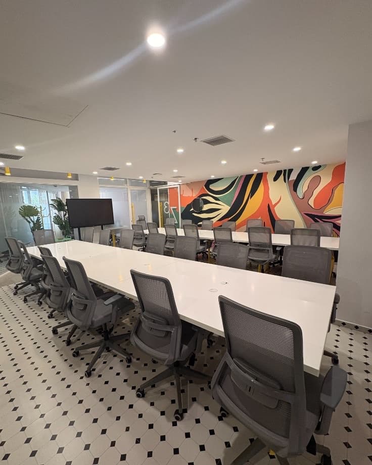 Corrivex meeting bay with white work tables, mesh chairs, and the colourful facility mural