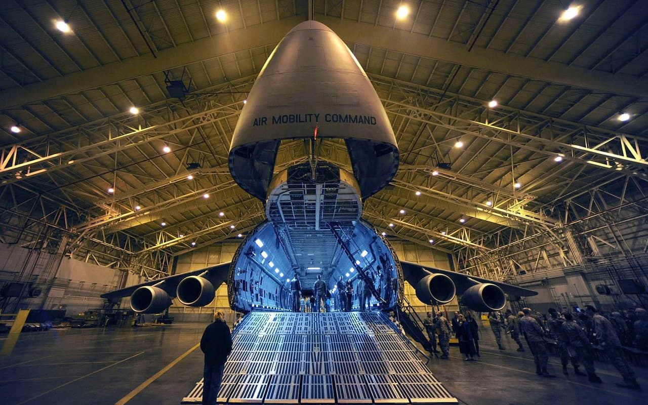 Air Mobility Command cargo aircraft with its nose door raised for loading inside a hangar — air freight operations taught at Corrivex