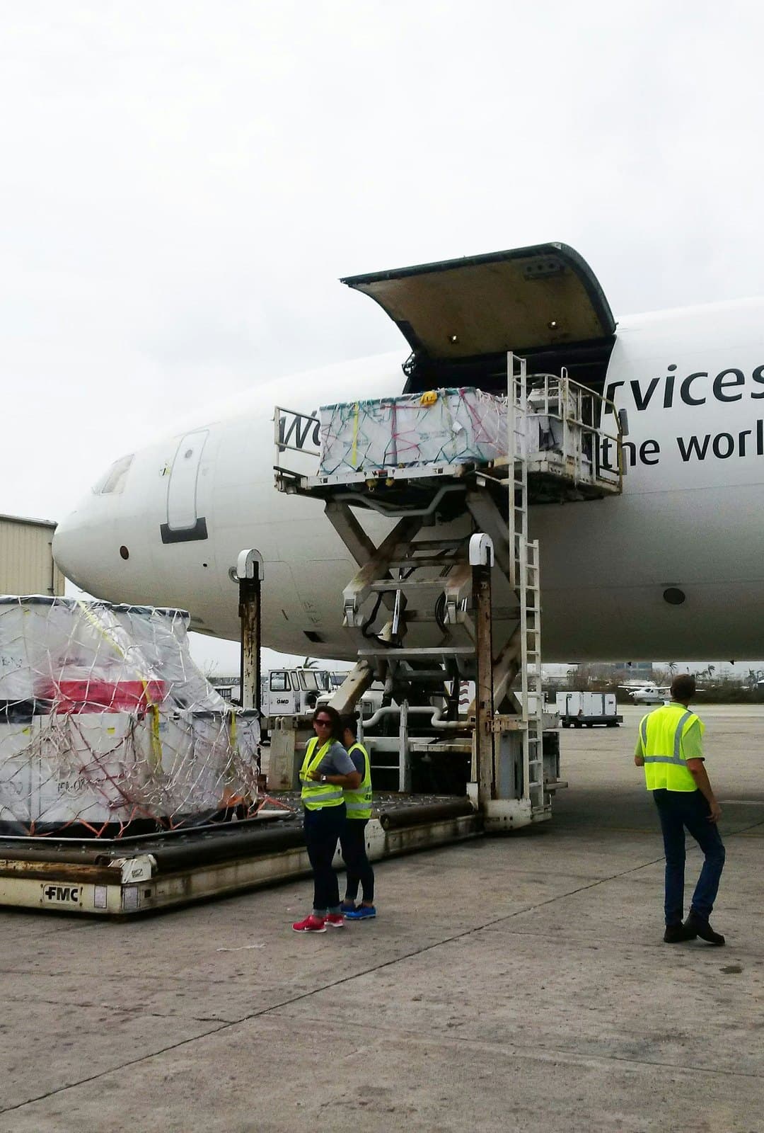 Ground crew loading pallets onto a wide-body cargo freighter via a scissor lift — air cargo handling and documentation training