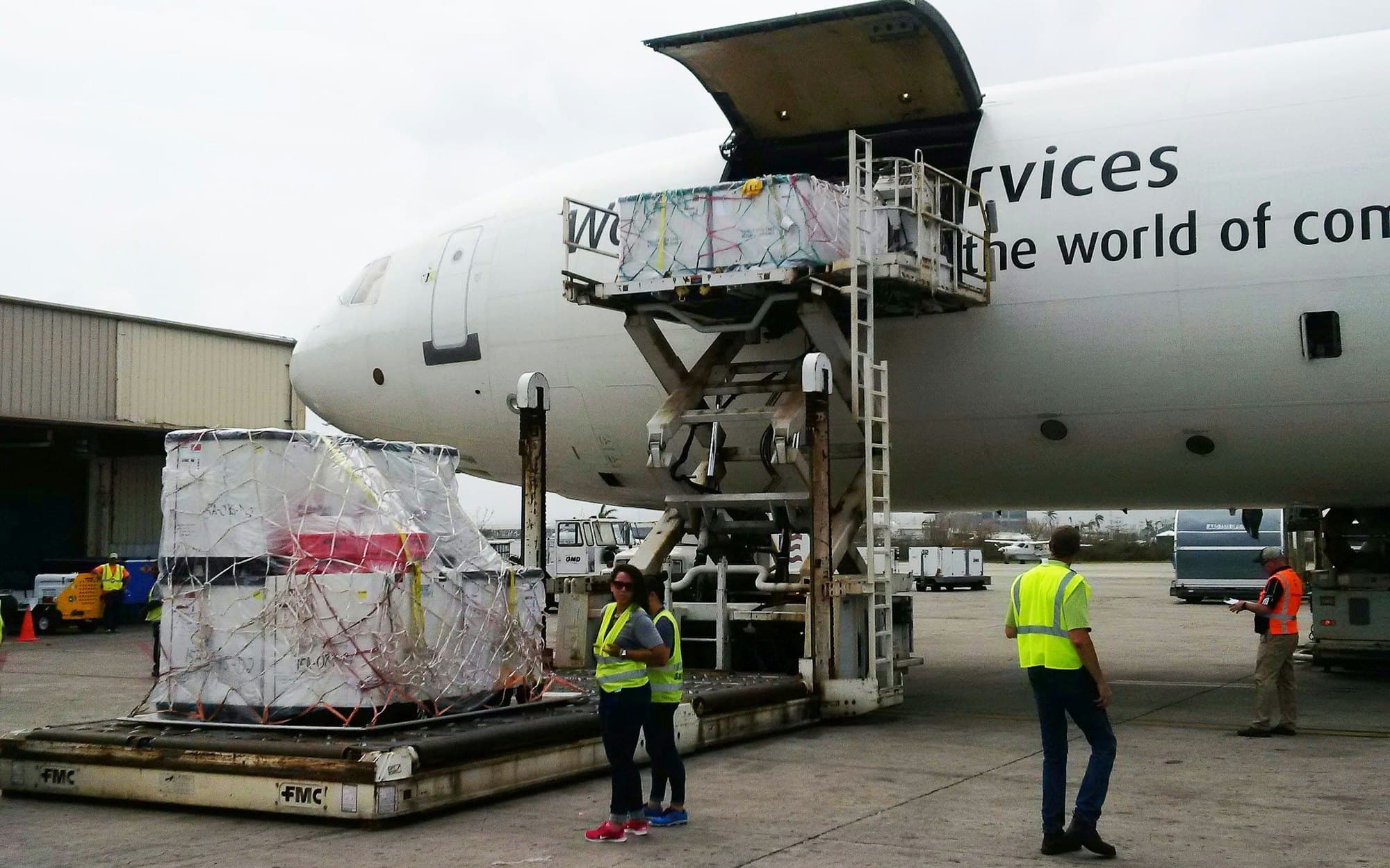 Ground crew loading pallets onto a wide-body cargo freighter via a scissor lift — air cargo handling and documentation training